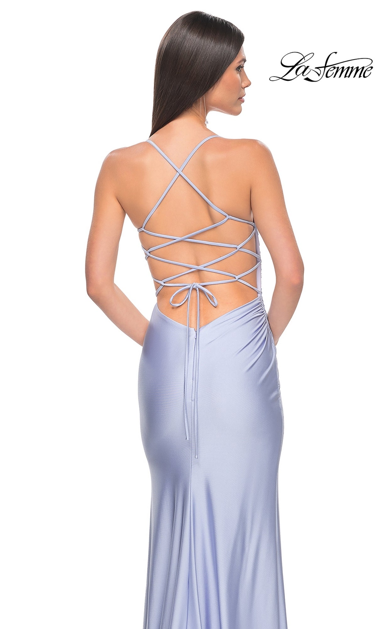 Woman wearing the La Femme Strappy Open-Back Long Prom Dress 31129 in light purple satin, featuring thin straps, a lace-up open back, and a fitted silhouette—perfect for prom. She stands facing away from the camera.